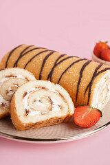 Plate with sweet sponge cake roll on pink background, closeup