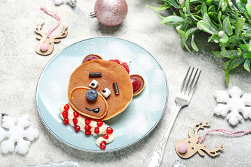 Plate with bear made of pancakes, fruits and Christmas decor on grunge table