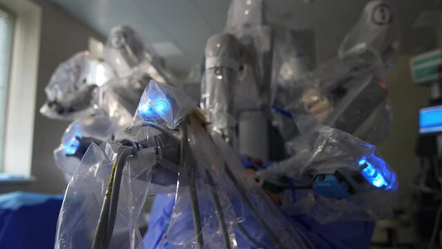 Blue lights on the tops of robotic arms in surgeon machine. Da Vinci surgery system carry out the operation. Close up. Blurred backdrop.