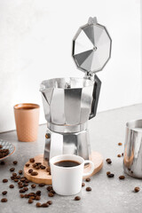 Geyser coffee maker, cup of espresso and beans on table against light background