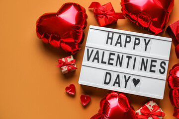 Board with text HAPPY VALENTINE'S DAY, balloons, candles and gifts on orange background