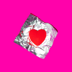 Heart candy in foil on bold pink background. Modern Valentine's Day concept. Creative love idea. Minimalistic Mother's Day composition.