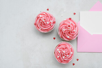 Tasty cupcakes and envelope with blank card for Valentine's Day on white background