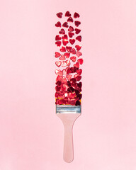 Red hearts and paint brush on pastel light pink background. Minimalistic love concept. Creative...