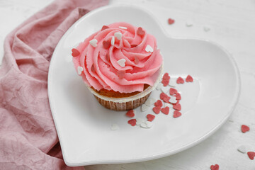 Plate with tasty cupcake for Valentine's Day on white wooden background, closeup