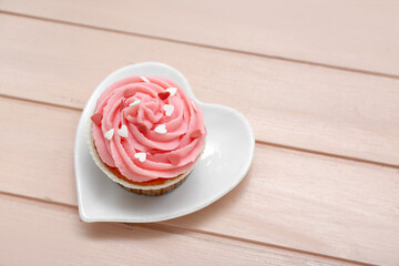 Obraz na płótnie Canvas Plate with tasty cupcake for Valentine's Day on color wooden background