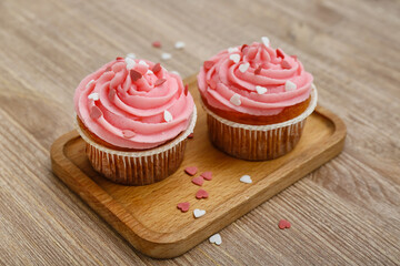Board with tasty cupcakes and hearts for Valentine's Day on wooden background