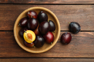 Tasty ripe plums on wooden table, flat lay