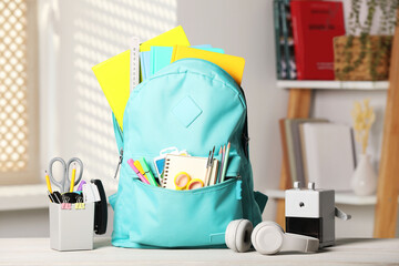 Turquoise backpack and school stationery on table indoors