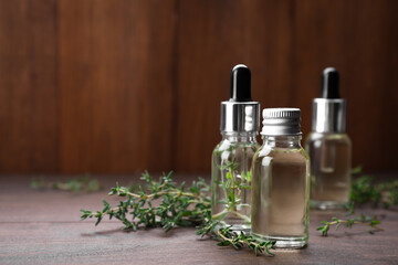 Thyme essential oil on wooden table, space for text