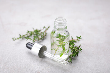 Thyme essential oil on light grey table