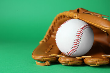 Catcher's mitt and baseball ball on green background, closeup with space for text. Sports game