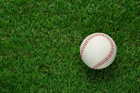 Baseball ball on green grass, top view with space for text. Sports game