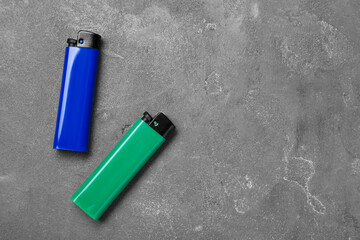 Stylish small pocket lighters on grey table, flat lay. Space for text