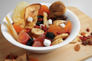 Bowl with different dried fruits on white background, closeup