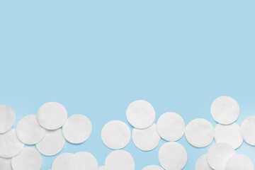 Many cotton pads on light blue background, flat lay. Space for text