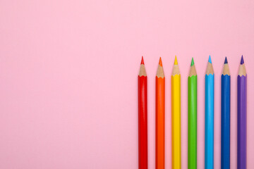 Colorful wooden pencils on pink background, flat lay. Space for text