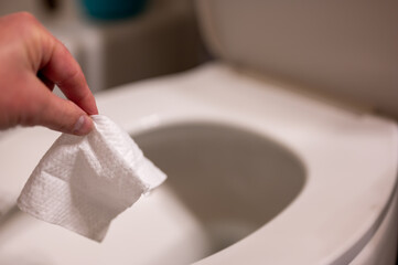 Disposable wipes being flushed down a toilet where they can cause clogging and problems with wastewater treatment. - obrazy, fototapety, plakaty