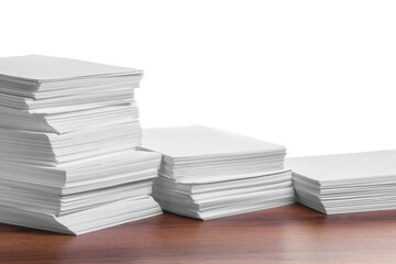 Stacks of paper sheets on wooden table against white background