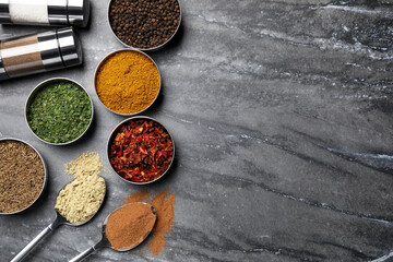 Flat lay composition with different spices on grey marble table, space for text