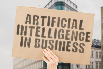 The phrase " Artificial intelligence in business " is on a banner in men's hands with blurred background. Intellectual. Mind. Tech. Virtual. Businessman. Connection. Creativity. Cyberspace