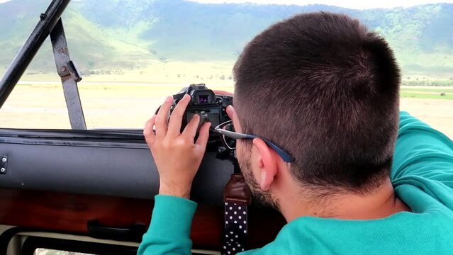 Young traveler checking camera photos during a 4x4 safari trip in Tanzania, Africa