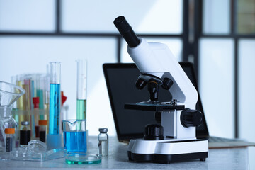 Modern microscope with glass slide on white table in laboratory, space for text