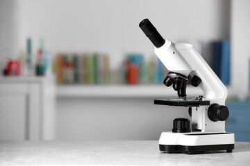 Modern medical microscope on white table in laboratory, space for text