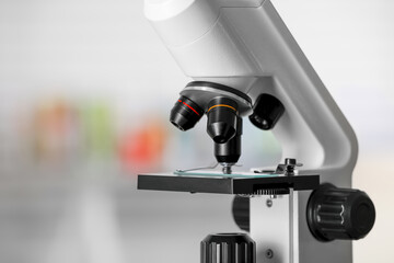 Modern medical microscope with glass slide on blurred background, closeup. Space for text