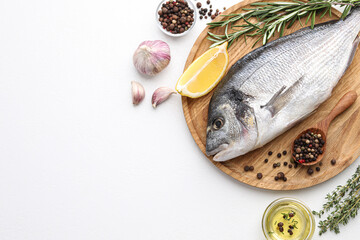 Flat lay composition with fresh raw dorado fish and ingredients on white table, space for text