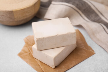 Blocks of compressed yeast on light gray table, closeup