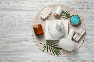 Composition of herbal bags and spa products on white wooden table, top view. Space for text