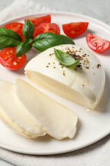 Delicious mozzarella with tomatoes and basil leaves on table, closeup
