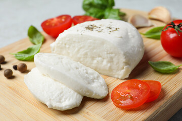 Delicious mozzarella with tomatoes and basil leaves on wooden board, closeup