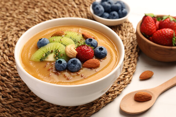 Delicious smoothie bowl with fresh berries, kiwi and nuts on table, closeup
