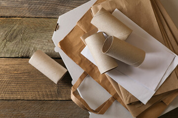 Stack of different waste paper on wooden table, flat lay. Space for text
