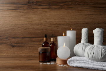 Fototapeta na wymiar Beautiful spa composition with different care products and burning candles on wooden table. Space for text