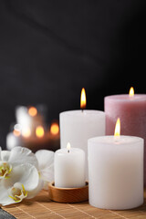 Fototapeta na wymiar Burning candles and flowers against black background. Spa therapy