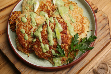 Tasty parsnip cutlets with sauce on wooden table, above view