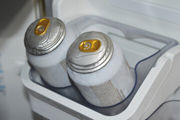 Two beer cans damaged and with bumps on the top because of too low temperature of the freezer.