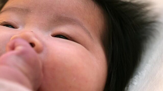 0歳3か月の乳児の赤ちゃんがこぶしを舐める様子の顔のアップを撮影した動画