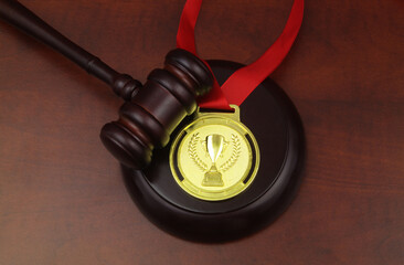 Top view of gold medal with champion cup image and ribbon with judge gavel on wooden table....