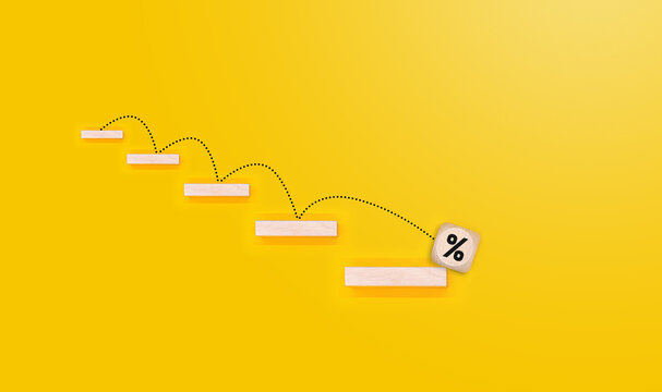 A cube on a yellow background with decreasing interest. Interest rates go down. Business concept.