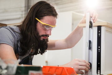 Professional carpenters using a  ruler and spirit level to measures a wood panel. 