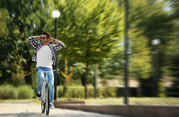 Handsome young man riding bicycle in park, motion blur effect