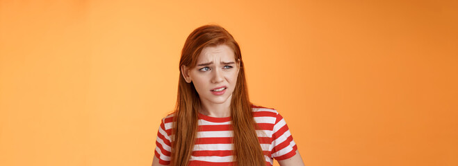 Close-up unsure redhead teenager frowning uncertain, having doubts, look perplexed left side copy space, hesitating, cringe dislike and disappointment, stare frustrated, uneasy decision