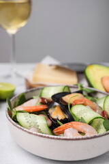 Bowl of delicious salad with seafood on light grey table, closeup