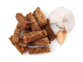 Delicious crispy rusks and garlic on white background, top view