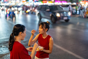 Happy Asian family on summer holiday travel vacation. Adult mother and daughter enjoy and fun outdoor city lifestyle shopping and eating street food together at Bangkok Chinatown street night market.