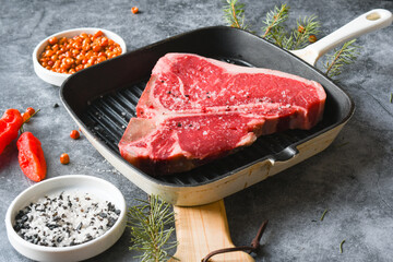 Raw T-Bone or porterhouse Steak in a grill pan with seasoning and Carolina reaper pepper